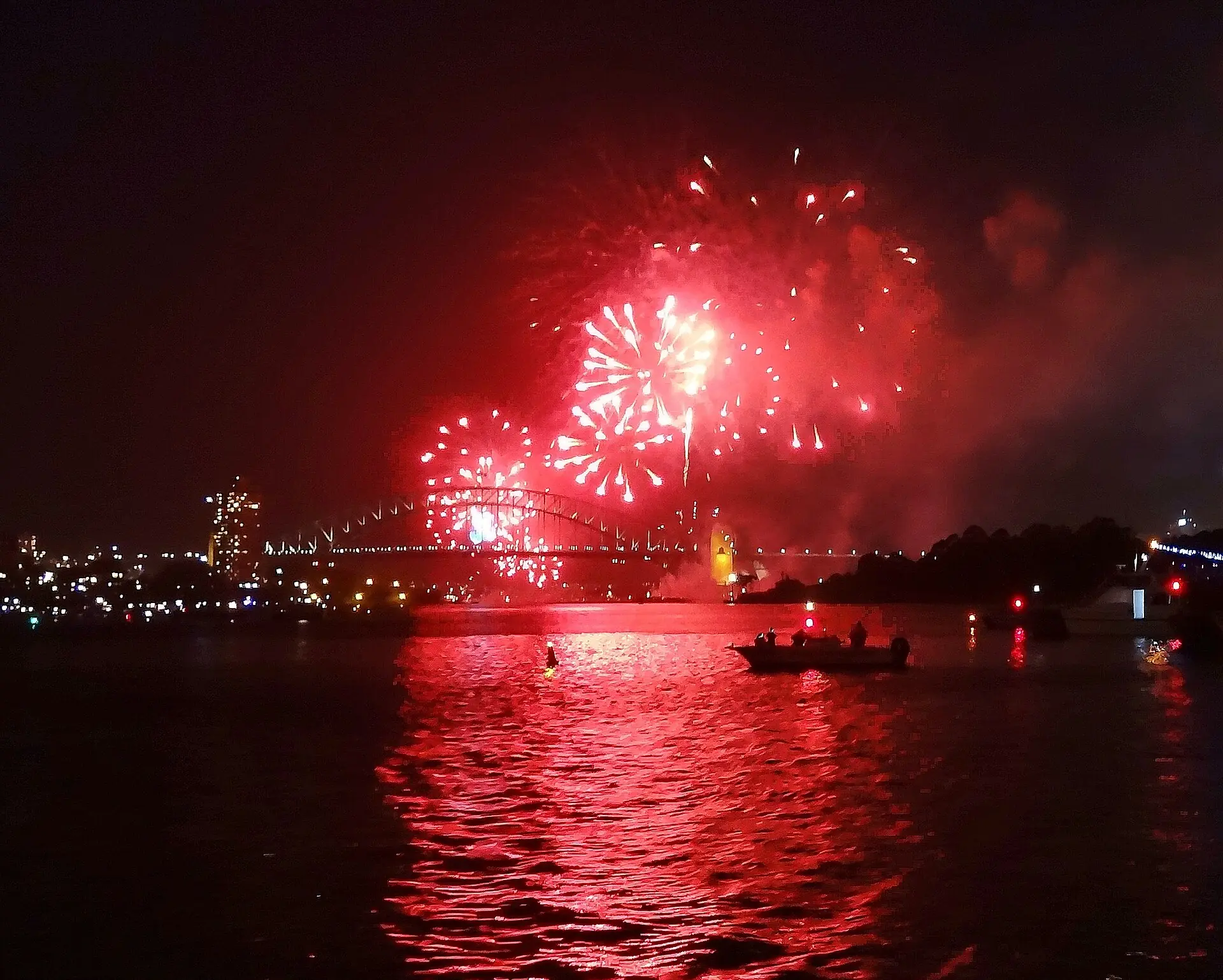 Red fireworks over the Harbour Bridge reflected across the water